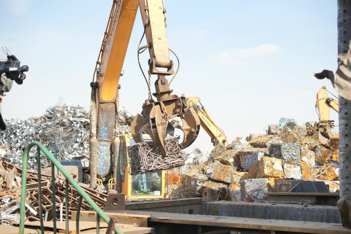 Bagger arbeitet auf einem Schrottplatz mit Altmetall